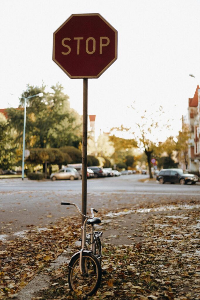 Stoppschild an herbstlicher Straße mit kleinem Fahrrad – Symbol für Grenzen manueller Zeiterfassung IT-Dienstleister