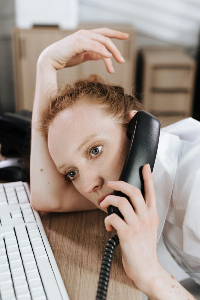 Erschöpfte Support-Mitarbeiterin am Telefon – Symbol für überlastete MSP-Teams ohne strukturierte Zeiterfassung Systemhaus